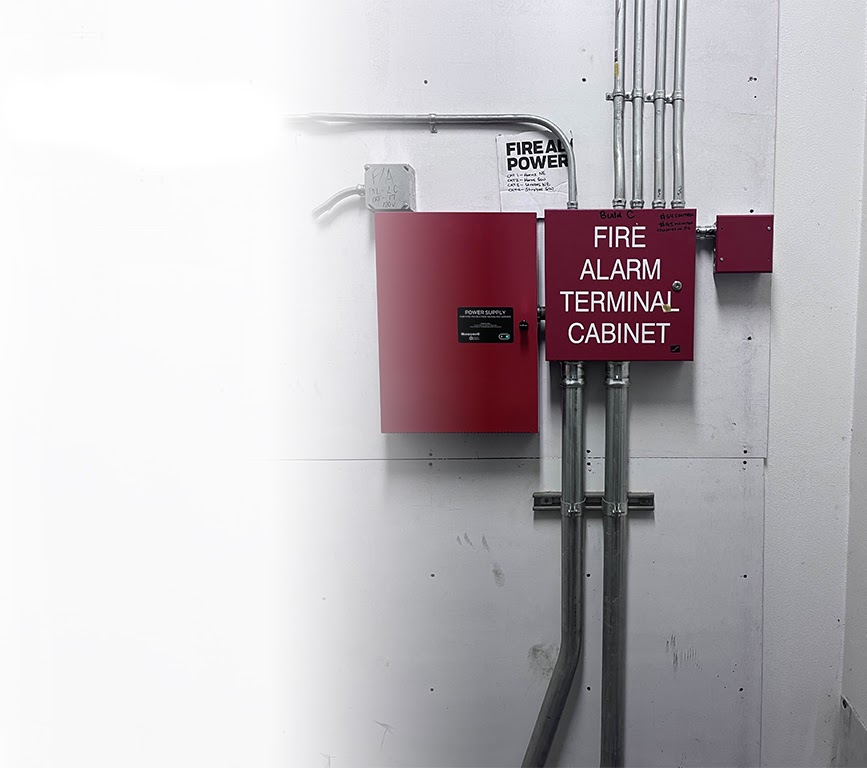Red fire alarm terminal cabinet with neatly routed metal conduit